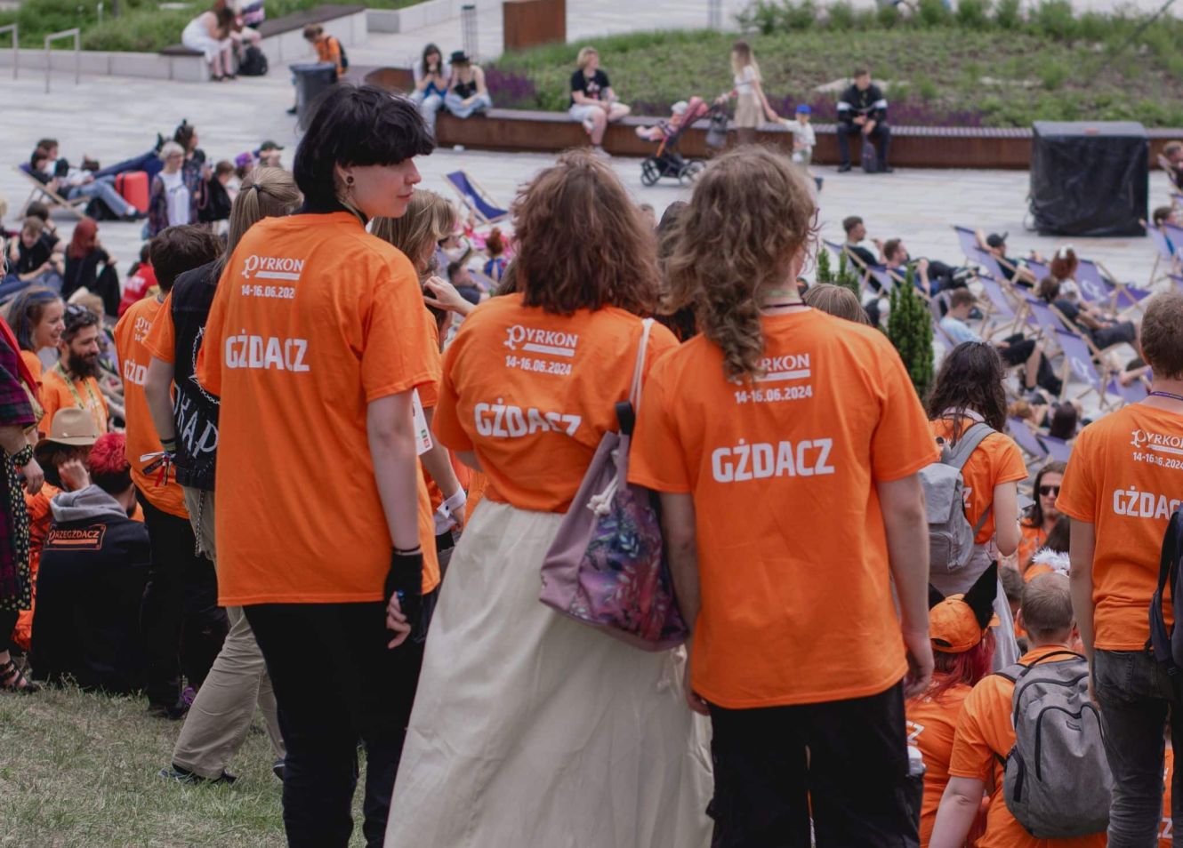 Photo of the volunteers standing backwards. On their orange duty T-shirts is written "gzdacz".